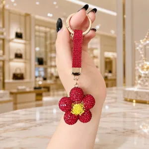 Red rhinestone sunflower keychain detail, sparkling crystal daisy bag charm pendant close-up.