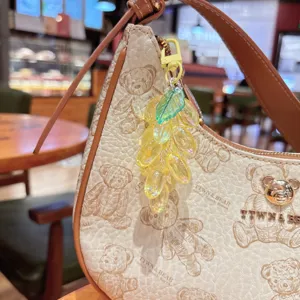 Primer plano detallado del colgante de uva de acrílico translúcido en bolso elegante.