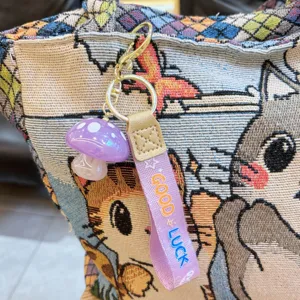 Close-up detail shot of a creative jelly mushroom keychain with purple resin pendant and strap.
