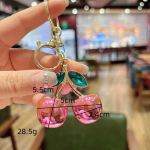 Cute pink crystal cherry keychain and bag charm with green rhinestone leaves and gold hardware.