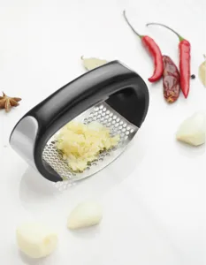 Detail shot of stainless steel garlic press with black curved handle, mincing garlic easily.