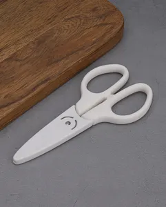Detailed close-up shot of white baby complementary food scissors with protective cover.