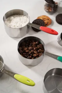 Stainless steel measuring cup detail view showing clear capacity markings and colorful handles.