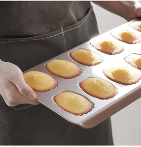 Detail shot of 12-cavity carbon steel Madeleine baking pan with shell shaped cakes inside.