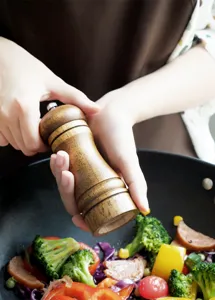 Detail van de houten pepermolen, handmatige molen, keukenscène met verse groenten tijdens koken.