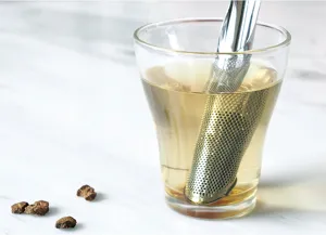 Detalle de barra infusora de té de acero inoxidable filtrando té en un vaso de vidrio.