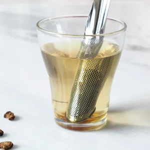 Bastón infusor de té de acero inoxidable en una taza de vidrio para té en hojas.