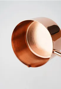 Gros plan sur la tasse à mesurer en or rose, montrant l'intérieur et le bec verseur.