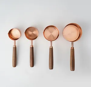 Gros plan détaillé des tasses à mesurer en cuivre avec des poignées en bois lisses.
