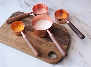 Set de tasses et cuillères à mesurer en or rose avec manches en bois pour la cuisine.