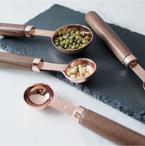 Gros plan cuillères à mesure or rose, métal plaqué cuivre avec manche en bois pour pâtisserie.