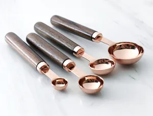 Set de cuillères à mesurer en or rose avec poignées en bois, ustensiles de cuisine et pâtisserie.