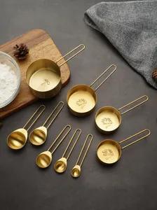 Stainless steel measuring cups and spoons set gold baking tools with clear scale.