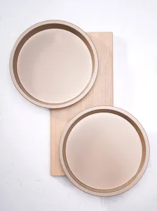 Detail shot of round gold non-stick baking pans displayed on a wooden board for kitchen use.