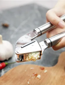 Stainless steel garlic press detail showing garlic crushing action in kitchen use.