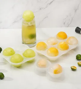 Silicone ice ball mold detail showing clear spherical ice makers with fruit inside on marble.