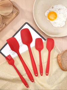 Vista detallada del juego de espátulas de silicona roja con pincel en la cocina.