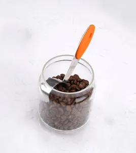 Stainless steel measuring spoon detailed view with orange handle and capacity markings.