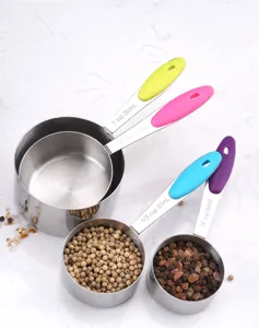 Detail view of stainless steel measuring cups with colorful handles filled with peppercorns.