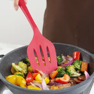 Red silicone cooking spatula in non-stick pan with stir-fried vegetables, kitchen tool main image.