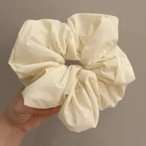 Detailed close-up view of a soft off-white large scrunchie, fluffy fabric hair accessory.
