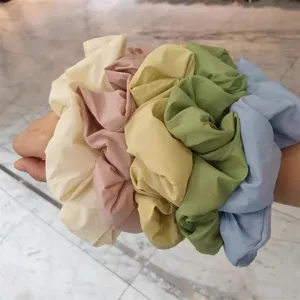 Close-up of multi-color fluffy scrunchies worn on wrist, showing soft pastel fabric texture.