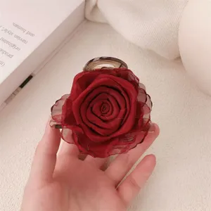 Close-up of red fabric rose hair claw clip, elegant tulle flower hair accessory detail.