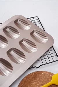 Detailed view of the 12-cavity gold Madeleine baking pan with non-stick coating closeup.