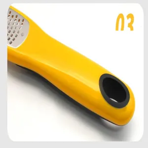 Close-up detail of yellow cheese grater handle with hanging hole and sharp stainless steel grating surface.
