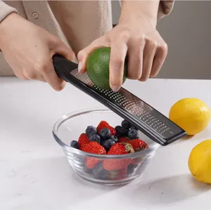 Detailed view of stainless steel cheese and lemon grater with ergonomic black handle for kitchen.