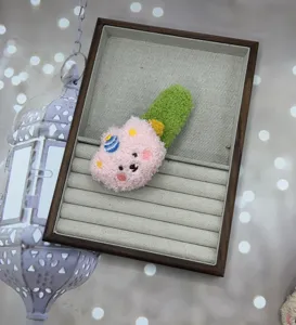 Detailed shot of the cute plush pudding bear hair clip in a tray, soft fabric texture.