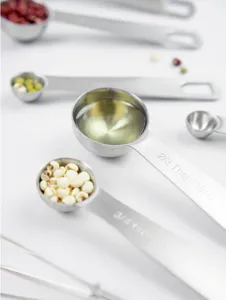 Stainless steel measuring spoon set detail showing clear engraved capacity markings for baking.