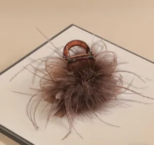Close-up detail of the elegant brown feather hair claw clip, showing fluffy texture.