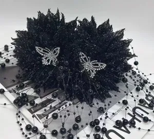Detailansicht einer eleganten schwarzen Blumen-Haarklammer mit Kristallschmetterlingen und Perlen.