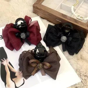 Close-up details of elegant mesh bow hair claw clips with shiny rhinestones in multiple colors.