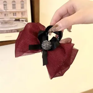 Detailed view of wine red mesh hair claw clip with black bow and sparkling rhinestone decor.