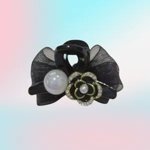 Detailweergave van zwarte mini haarclip met strik, parel en strass camelia bloem decoratie.