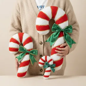 Detailed shot of Christmas plush candy cane pillows with green bows, soft holiday home decor.