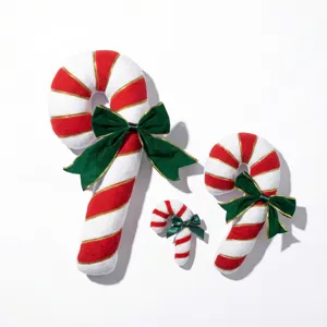 Detailed view of plush Christmas candy cane pillows with green bows, festive holiday decor.