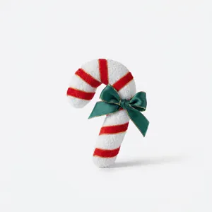 Detailed view of plush Christmas candy cane ornament with red stripes and green satin bow.