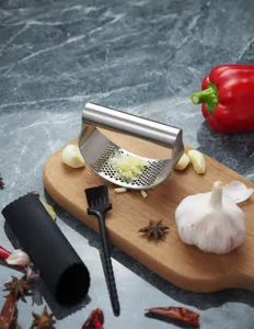 Stainless steel rocker garlic press detail shot showing manual mincer on kitchen board.