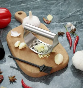Stainless steel garlic press in kitchen scene with fresh garlic cloves and wooden cutting board.