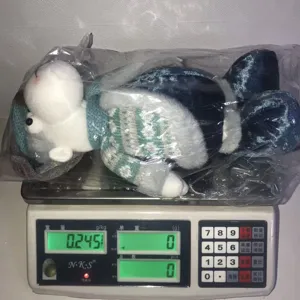 Detail view of the Christmas plush toy in knitted sweater on a digital scale showing weight.
