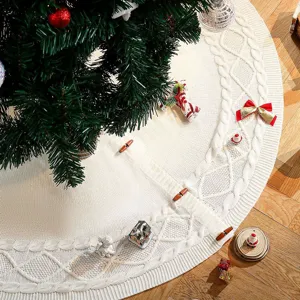 Vue détaillée de la jupe de sapin de Noël tricotée blanche avec motif torsadé et boutons.