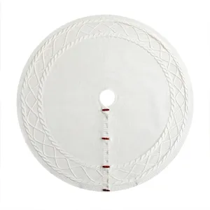 Détail de jupe de sapin de Noël en tricot blanc, motif torsadé et boutons en bois.