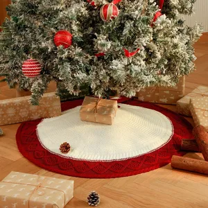 Detailed view of knitted Christmas tree skirt with red border and white diamond pattern.