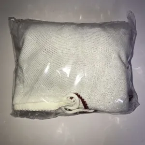 Vue détaillée de la jupe de sapin de Noël tricotée rouge et blanche pliée dans l'emballage.