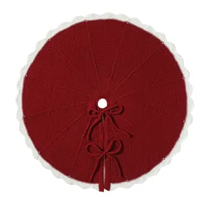 Detailed view of the red knitted Christmas tree skirt with white scalloped edge and bows.
