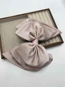 Elegant pink satin bow hair clip, large hairpin for women and girls ponytail styling accessory.
