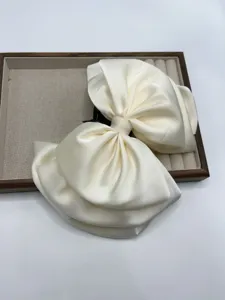 Cream satin bow hair claw clip detail shot, elegant fabric hair accessory display.